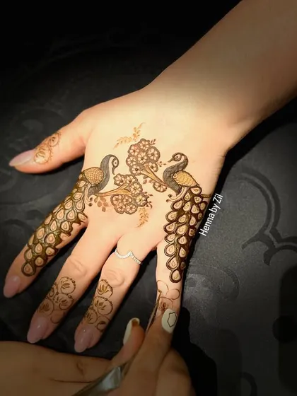 A very delicate and artistic design. Two peacocks create a beautiful pattern on the back of the hand, with their feathers flowing down the fingers.