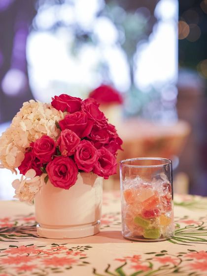 A simple, elegant detail of a small bouquet of red and white roses next to a refreshing drink, showing how decor extends to every part of the guest experience.