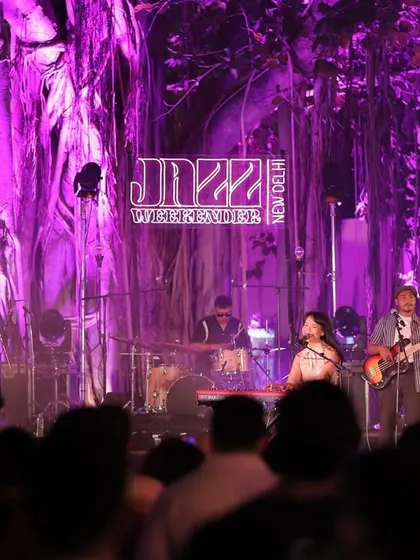 A live band captivates the audience on the Jazz Weekender stage. The purple lighting against the natural backdrop of the banyan tree is a signature part of the festival's visual and atmospheric design.