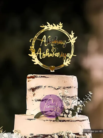 A mockup of the "Akshay & Ashwariya" wreath topper on a rustic-chic cake, perfect for an outdoor or barn wedding.