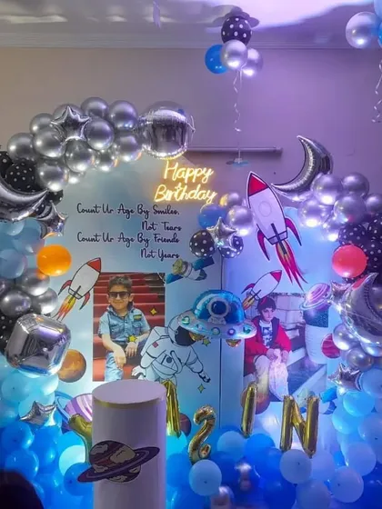 A detailed space-themed birthday party with custom photo backdrops, rocket cutouts, and a balloon arch.