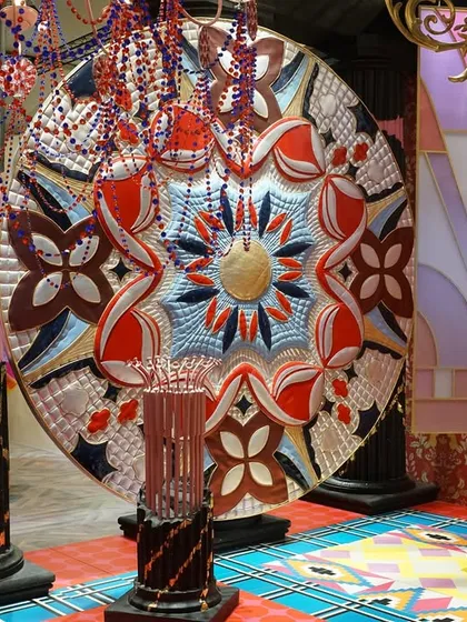 A large, circular textile artwork from the 'Bad Taste?' installation. The piece is an unabashedly loud and decadent display of color and pattern, challenging conventional notions of taste.