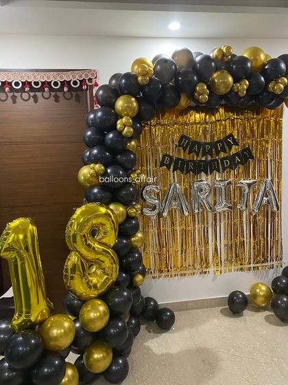 A close-up of the 18th birthday balloon arch, highlighting the mix of black and gold balloons.