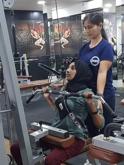 One-on-one guidance is a key part of our training. Here, an instructor provides personalized feedback to a student on the lat pulldown machine, ensuring she understands the correct posture and muscle engagement for this back-strengthening exercise.