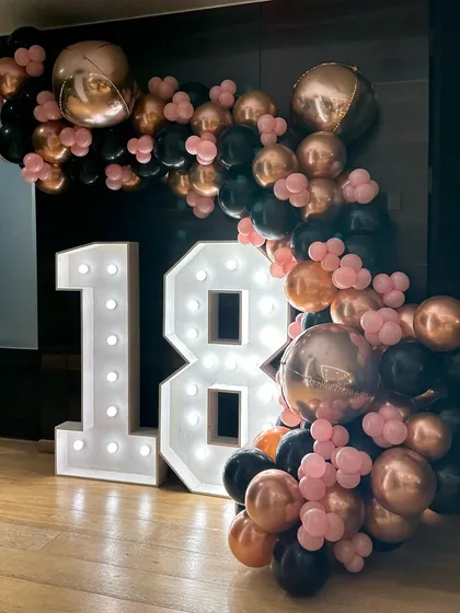 An 18th birthday is a big deal, and we marked the occasion with large, light-up marquee numbers and a sophisticated balloon garland in a rose gold and black color palette.