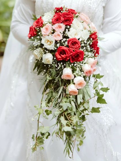 A cascading bouquet of red, pink, and white roses held by the bride. The choice of flowers and colors perfectly complemented the red and white theme of the church decor, tying everything together beautifully.