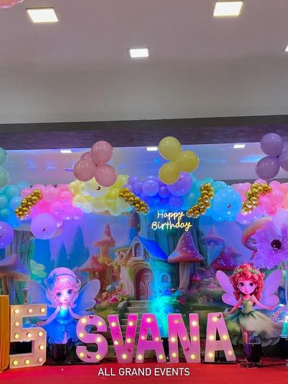 A straight-on view of the fantasy stage setup, showing the arrangement of props, balloons, and the glowing marquee name and number.