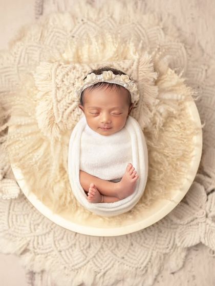 An artistic composition with a newborn nestled in a bowl, surrounded by delicate macrame. This highlights the creative setups I design.