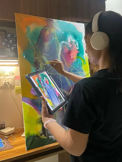 The art I create is a direct reflection of how I am feeling or what I am dreaming. Here I am using a tablet for reference while working on a large canvas, making sure the digital sketch translates perfectly into a physical painting.