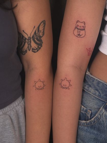 Friendship tattoos. These matching suns, along with a butterfly and a lucky cat, are permanent symbols of a cherished bond.