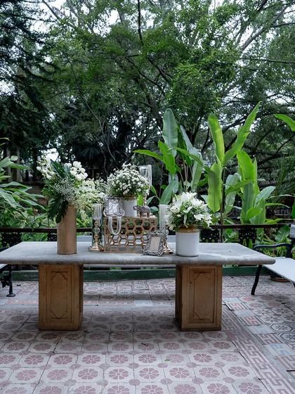 A sangeet setup in the garden, with a stone table decorated with flowers, ready for an evening of music and dance.