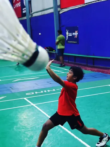 Focus on the shuttle. A player prepares to execute a precise net shot, demonstrating the control and delicate touch we teach for dominating the front of the court.