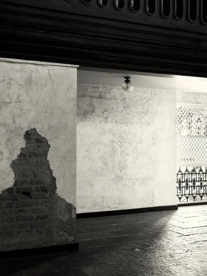 A passageway showing the aged wall texture, dark stone floors, and a glimpse of decorative ironwork, all contributing to the old-world narrative.