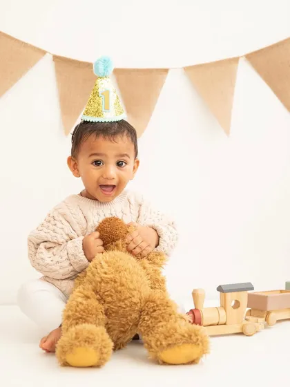 A birthday hat and a best friend. This little boy is all smiles as he celebrates turning one with his favorite teddy bear.