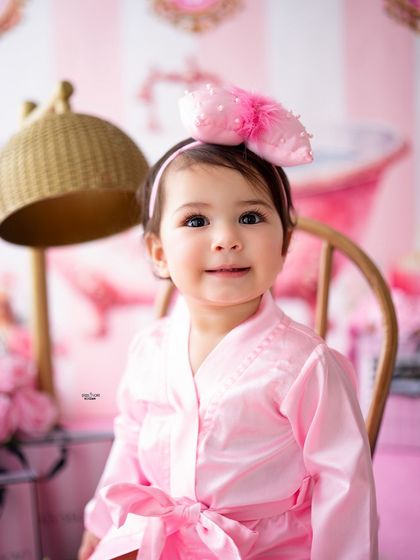 A sweet, direct-to-camera portrait of this baby girl in her pink spa day setup.