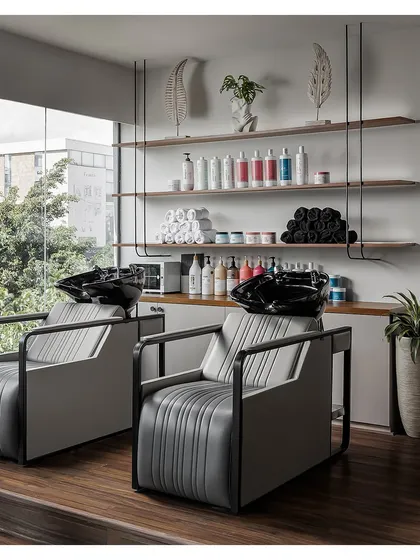 The hair wash station is designed for relaxation and efficiency, with comfortable, ergonomic chairs and open shelving for easy access to products.