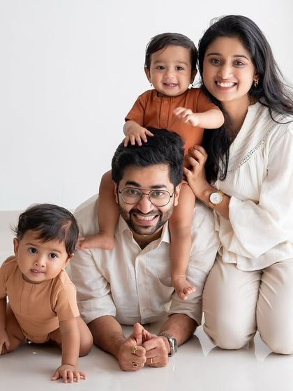 A happy family of four posing for a studio portrait.