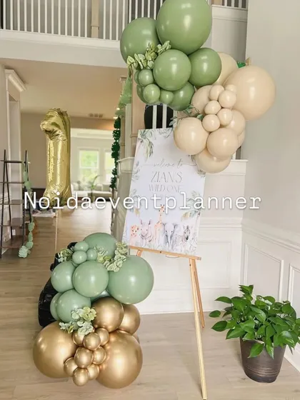 The welcome area for a jungle-themed party, featuring a personalized sign on an easel decorated with matching sage green and gold balloons.