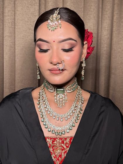 A classic bridal look with soft smokey eyes and a neutral lip. The red rose in her hair adds a traditional touch to this modern, flawless glam. Dates for the 2025-26 wedding season are filling fast.