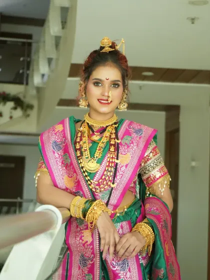 A full-length portrait of the Peshwai bride, looking regal in her green and pink Paithani saree and heavy gold jewellery.