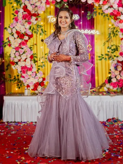 The bride looks radiant in this lavender fish-cut lehenga. The sequin work and ruffled details create a modern, glamorous look that is perfect for an evening celebration.