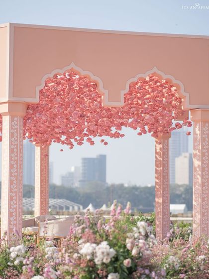 The mandap's floral ceiling and hand-painted pillars, with the modern cityscape visible in the background, creating a beautiful juxtaposition.