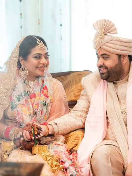 A sweet moment between a couple during their wedding rituals. Their gentle smiles and held hands speak volumes.