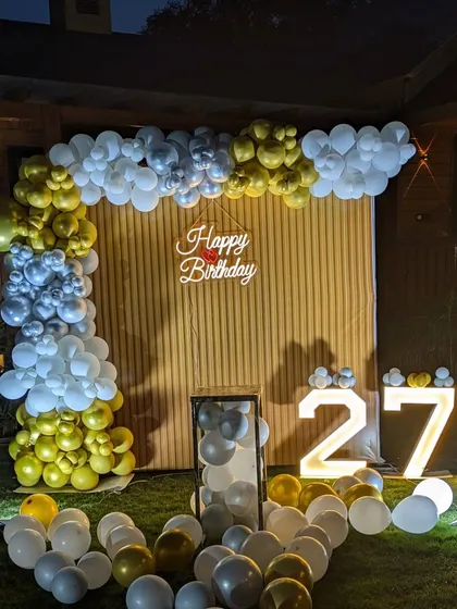 I also arrange decorations for outdoor celebrations, like this 27th birthday party in a garden. The setup includes a custom balloon arch, a neon sign, and large light-up marquee numbers for a festive touch.