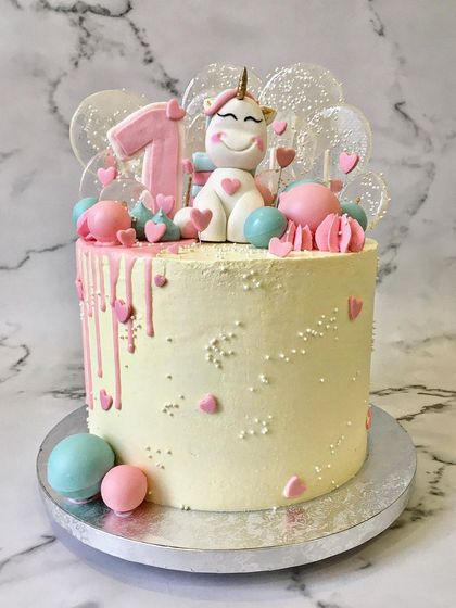 Another take on the magical unicorn theme, this one for a first birthday. It features a cute, hand-sculpted fondant unicorn, a pink drip, and clear isomalt lollipops for a touch of sparkle.