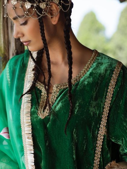 A portrait for Baavli, taken in the mountains. The rich green velvet and traditional headpiece are set against a rustic wooden backdrop.