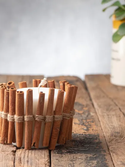 This is one of my signature designs: a pillar candle wrapped in real cinnamon sticks. It releases a wonderful, warm scent, especially when the candle is lit.