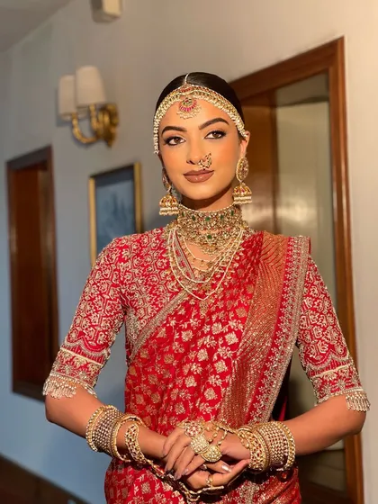 A complete South Indian bridal look featuring a sleek, center parted bun. The hairstyle is designed to perfectly accommodate the traditional matha patti and jhumkas, creating a regal and authentic bridal profile.
