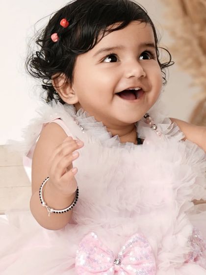 A baby is as pure as an angel. This close-up shot captures the joyful and innocent expression of a baby girl in a beautiful pink dress.