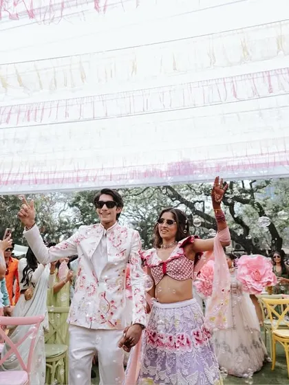 The couple makes their way through the crowd, waving happily. This candid shot captures the energy and joy of their entrance.