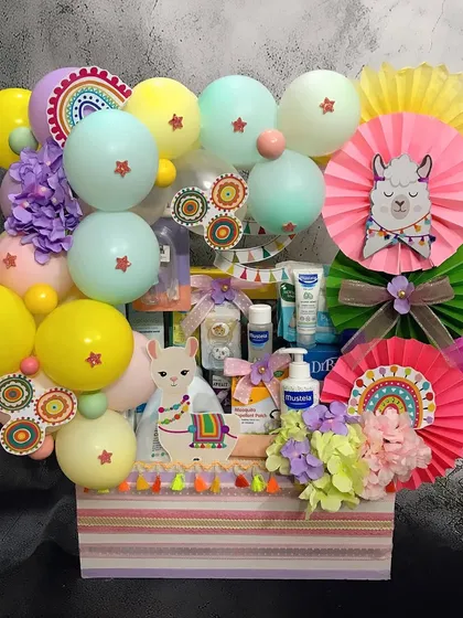 A closer look at our 'No Drama Llama' themed gift hamper, filled with baby care essentials from Mustela. The colorful paper fans and llama cutouts make it extra cheerful.