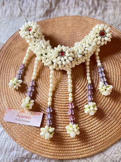 A beautiful hair brooch designed to be worn with a bun or braid. This piece is made from fresh white flower buds and accented with red and purple details.