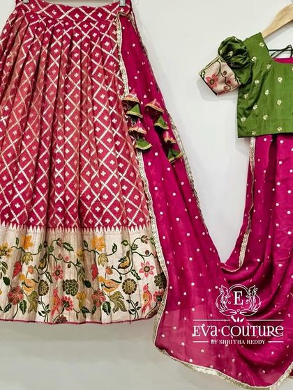 A modern half-saree set with a pink diamond-patterned lehenga featuring a floral border, paired with a green blouse and pink dupatta.