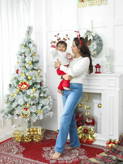 A full-length view of our cozy Christmas corner, capturing a mother holding her laughing child. It's a perfect scene for a family holiday card.