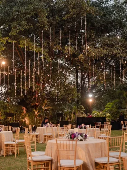 A wide view of this minimalist and elegant pre-wedding gala. The outdoor lawn was transformed with simple round tables, beautiful floral centerpieces, and a canopy of hanging lights that created a magical glow as evening fell.
