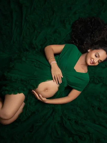 An artistic overhead shot, with the mother-to-be nestled in a sea of emerald green tulle. This perspective creates a unique and stunning fine art portrait.