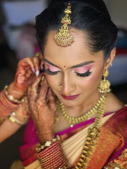 A close-up of the bride's makeup, with a focus on the vibrant pink eyeshadow and flawless skin.