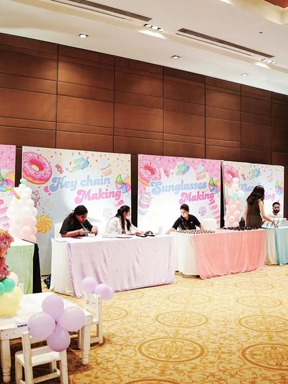 A row of activity stations set up for a Candyland party. The stations included face painting, key chain making, and other crafts to keep kids engaged.