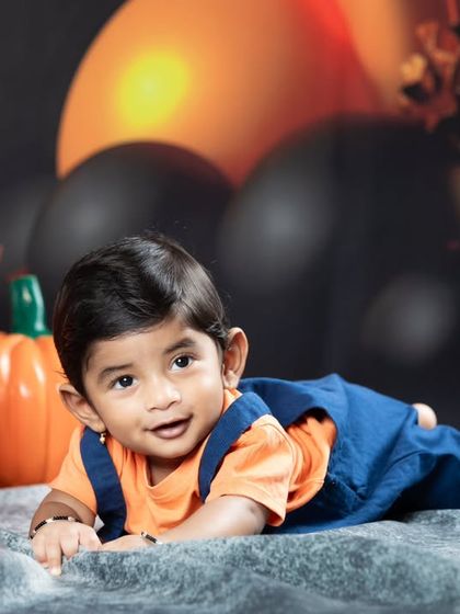 A happy baby crawling in front of the Halloween decorations.