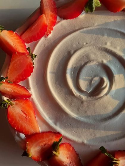 A top-down view of the strawberry cake, showing the swirl in the cream and the heart-shaped arrangement of the fresh berries.