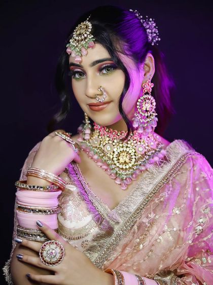 A soft, romantic bridal look in pastel pink, featuring delicate jewelry and a fresh, dewy makeup finish.