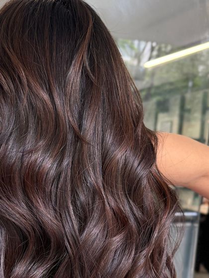 A detailed view of the deep brunette waves, highlighting the glossy finish and healthy appearance of the hair.