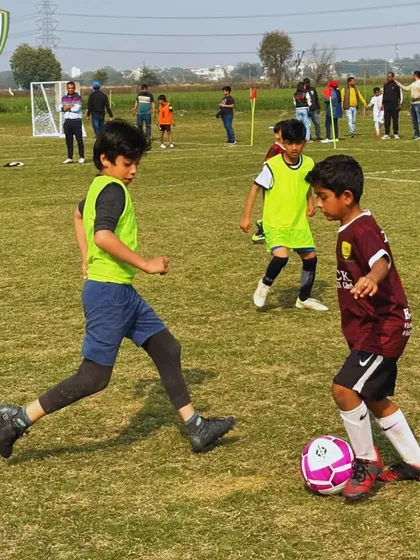 A young player shields the ball from a defender, demonstrating the strength and ball control skills we teach at our academy.