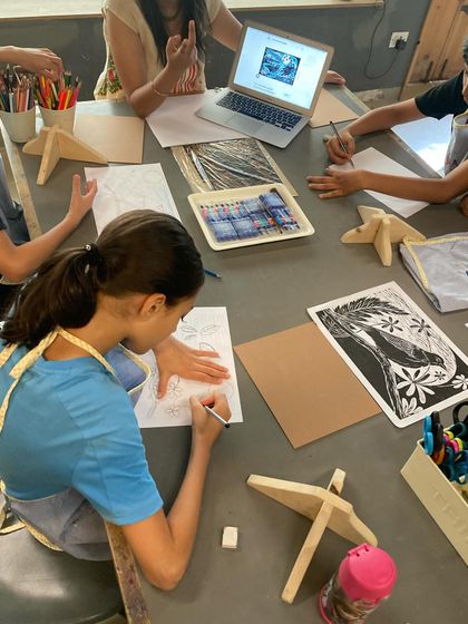 The creative process begins with an idea. Here, students are sketching their designs, looking at examples for inspiration before they begin the hands-on work of carving their plates for a woodcut printing session.