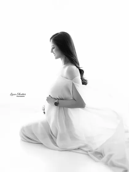 The simplicity of black and white photography allows the emotion of the moment to shine through. This quiet, contemplative portrait in a flowing gown captures the serene beauty and inner glow of pregnancy in a timeless way.