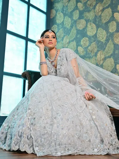 A dramatic pose by the window, with the light catching the sheer dupatta. The makeup is designed to look beautiful in all lighting conditions, from soft and natural to dramatic.